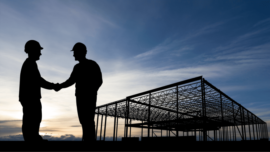 Two business owners shaking hands as partners, at a construction sight.